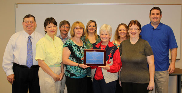 THE STAFF of Missouri State University-West Plains’ student services department won the “Highest Dollar Amount Raised” award in the departmental contest at the university’s 19th annual auction April 5.  This is the fourth consecutive year the department has won the award.  On hand for the plaque presentation were, front row from left, Drago College Store Manager Kathy Schloss, Food Services Manager Mozella Jett, Career Services Assistant Coordinator Alice Smith, and Financial Aid Clerk Becky Craig; back row: Dean of Student Services Dr. Herb Lunday, Coordinator of Student Life & Development Rogers Taylor, Registrar Shanna Dale, Coordinator of Admissions Melissa Jett and Grizzly Basketball Head Coach Yancey Walker.  (Missouri State-West Plains Photo)