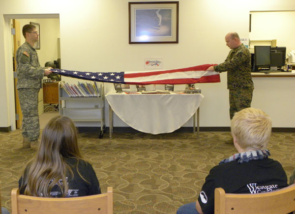 MISSOURI STATE UNIVERSITY-West Plains students William Hatcher, left, West Plains, and Greg Phipps, Willow Springs, both of whom are veterans of the armed services, demonstrate how to properly fold the United States flag as part of a community service project for Connie Yates’ College Reading and Study Skills (IDS 150) class on Veterans Day Nov. 11.  The veterans conducted the demonstration to members of Sylvia Hershenson’s third grade class at West Plains Elementary School during a visit to the Garnett Library.  Hatcher and Phipps discussed the importance of Veterans Day and answered questions from the students.  Following the demonstration, the students attended the annual Veterans Day Parade.  Hatcher was a Sergeant E5 in Alpha Troop of the 710th Cavalry in the U.S. Army 4th Infantry Division’s 1st Brigade at Fort Hood, Texas, at the time of his discharge.  Phipps was a Corporal in the 2nd Battalion, 9th Marines, 2nd Marine Division at Camp Lejune in Jacksonville, N.C., at the time of his discharge.  (Missouri State-West Plains Photo)