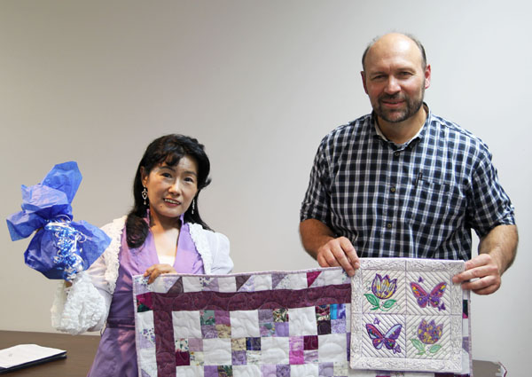DR. AYA KUBOTA, professor of American literature at Bunka Gakuen University in Tokyo, Japan, receives a locally-made pillow sham, quilted lap blanket and a Grizzlies coffee mug from Dr. Phillip Howerton, associate professor of English at Missouri State University-West Plains, at this year’s Ozarks Studies Symposium. Kubota joined Dr. John Han, professor of English and creative writing at Missouri Baptist College, to discuss “A Place of Restoration, Recreation, and Safety: The Ozarks in The Shepherd of the Hills, The Bald-Knobbers and The Witness” during the symposium Sept. 18-19 at the West Plains Civic Center. This year’s theme was “The Lure of the Ozarks.” (Missouri State-West Plains photo)