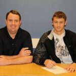 FRESHMAN GRIZZLY BASKETBALL player Desmond Buerge, right, of Carthage, Mo., recently signed a national letter of intent to complete his collegiate playing career at Cameron University in Lawton, Okla. Joining him as he signs his paperwork is Missouri State University-West Plains Grizzly Basketball Head Coach Yancey Walker. (Missouri State-West Plains Photo)