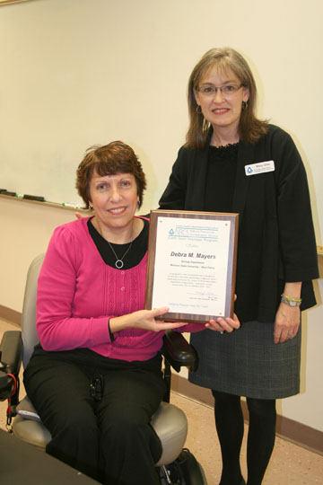 DEBRA MAYERS, left, assistant professor of biology at Missouri State University-West Plains, recently received an award of appreciation from the United States Department of Agriculture-Natural Resources Conservation Service (USDA-NRCS) for her “development and oversight of conservation partnerships in Missouri.” Beginning in 2010, Mayers signed up her biology students to participate in the NRCS’ Earth Team Volunteer Program to help educate area youngsters about the importance of protecting and conserving natural resources. Since that time, 81 biology students have taught natural resource lessons in 20 area communities reaching 1,529 children and educators. Mayers received the award from NRCS State Earth Team Coordinator Mary Giles. (Missouri State-West Plains Photo)