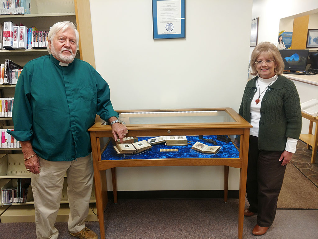 LOCAL AUTHOR ROBERT H. (BOB) WILLIAMS, left, has donated several items to the Garnett Library at Missouri State University-West Plains, including books, artifacts and a display case in recent years. His first donation of books was presented in 2014, and a subsequent donation of artifacts, including arrowhead fragments, was given later that same year. These donations have been catalogued and added to the library’s Missouri history collection, according to Director of Library Services Sylvia Kuhlmeier, with Williams above. In 2016, Williams contributed funds toward the purchase of a display case, and at the time this photo was taken earlier this fall, he presented another copy of his book “Billy’s War” to the library’s collection. A Missouri native, Williams is a former rector and career chaplain whose historical novel about the Civil War traces the life and times of his ancestors living in the “border wars” area of Missouri. Williams has said the gifts “have been a labor of love” for him, as he learned from family accounts and state history resources. (Photo provided)