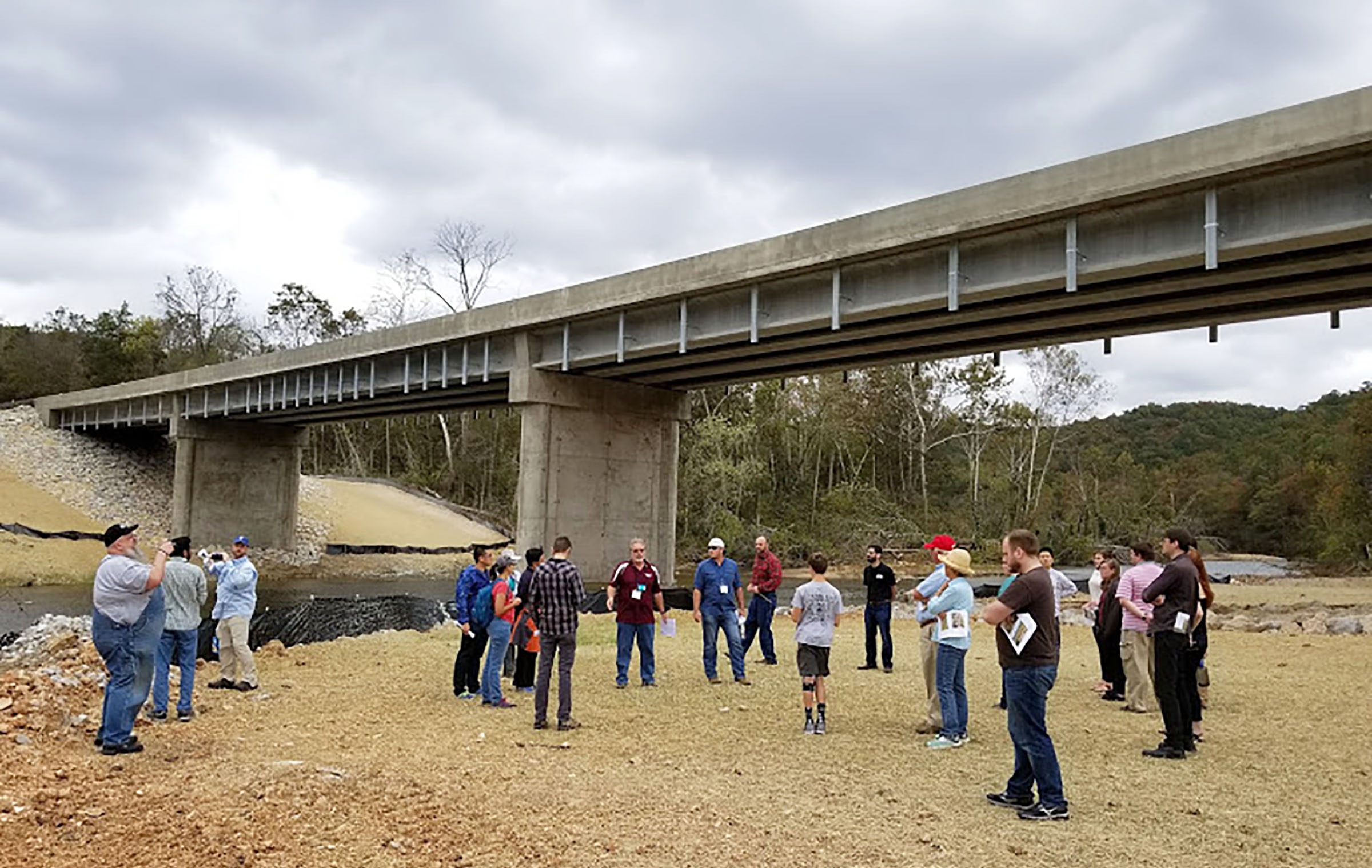 SEVERAL OF THOSE ATTENDING the American Association of Geographers-West Lakes Division (AAG-WLD) annual meeting gathered with Missouri State University Distinguished Professor Dr. Robert Pavlowsky near the new Highway CC bridge over the North Fork River to discuss global warming and its effects on flooding in the Missouri Ozarks. The original bridge, which stood over 40 feet above the river, was washed away by flash flooding in April this year. (Photo provided)