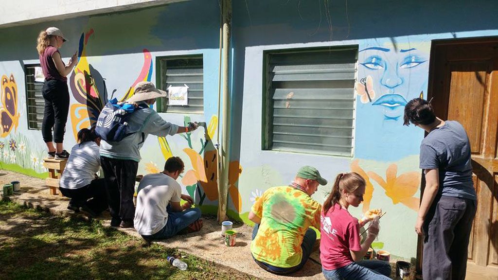A DESIGN CREATED by Darr Honors Program student Melinda Lee, West Plains, was so well liked, officials at the National School of the Environment and Natural Resources in the Dominican Republic allowed her and other members to paint the sketch on one of the buildings. From right are Lee, Destiny Johnson of Bakersfield, Darr Honors Program Director Alex Pinnon, Weston Phipps of West Plains, and other workers at the school. (Photo provided)