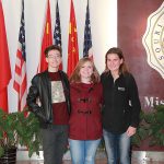 The students stand in front of the American and Chinese flags and university logos at the campus in China.