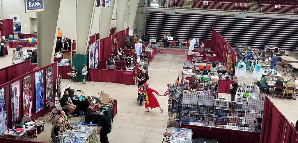 A bird's eye view of the West Plains Civic Center arena with various vendor booths and people at the 2018 Oz-Con convention.
