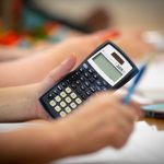 A close-up view of a student holding a calculator in class.