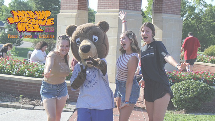 Three students take a picture with Grizz at last year's Welcome Week