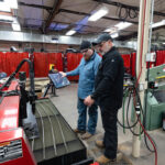 Welding student and instructor program a machine to cut out bear shape from a sheet of steel.
