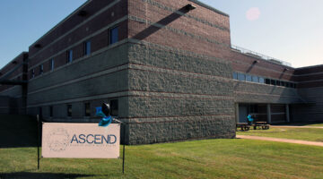 Building exterior with a banner in the yard that says "ASCEND"