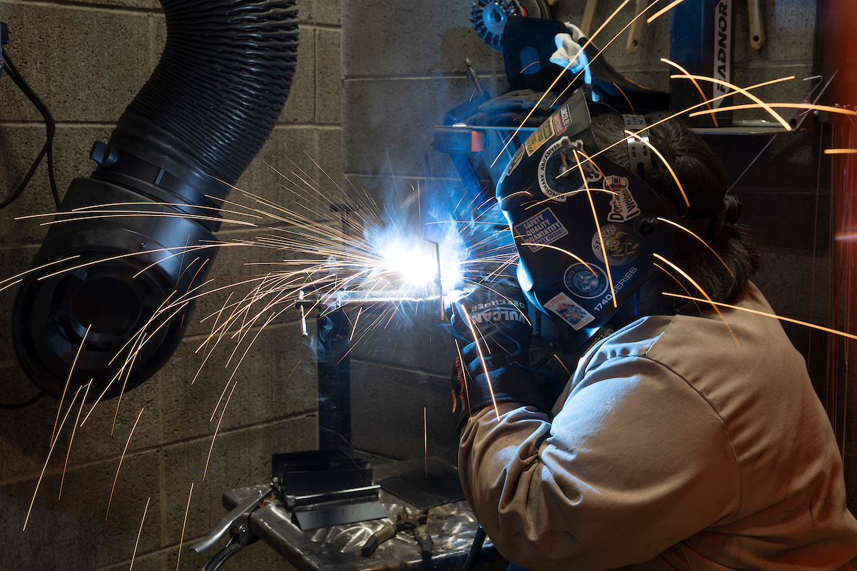 A student practices welding techniques in full protective gear.