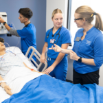 nursing students work with an instructor in the simulation lab