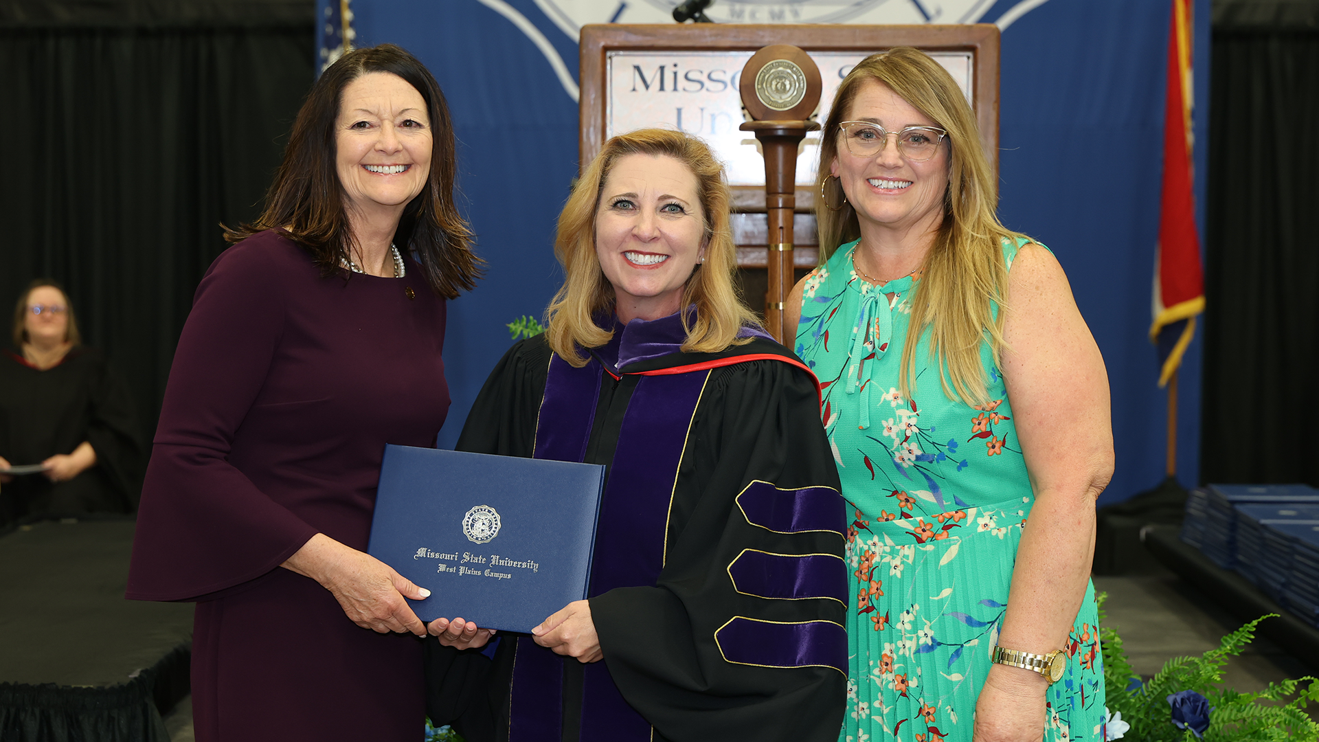 Chancellor Mulligan presents the honorary degree to Sgt. Daugherty's two daughters Dr. Caron Daughtery-Mitchell and Ms. Casey Daughtery.