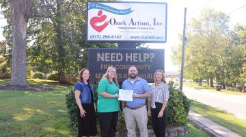 Shawna Hammon and Trevor Cressman pose for a group photo in front of the Ozark Action, Inc. sign with Ozark Action employees Holly Tucker and Angie Kinder