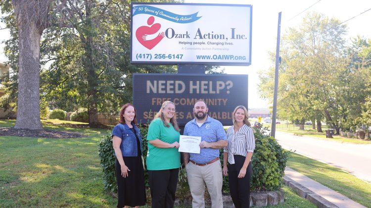Shawna Hammon and Trevor Cressman pose for a group photo in front of the Ozark Action, Inc. sign with Ozark Action employees Holly Tucker and Angie Kinder