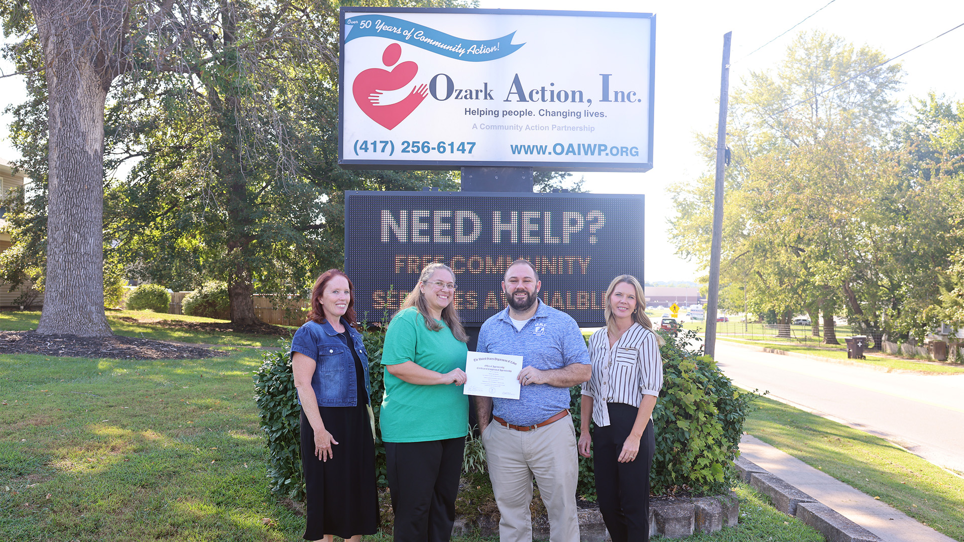 Shawna Hammon and Trevor Cressman pose for a group photo in front of the Ozark Action, Inc. sign with Ozark Action employees Holly Tucker and Angie Kinder